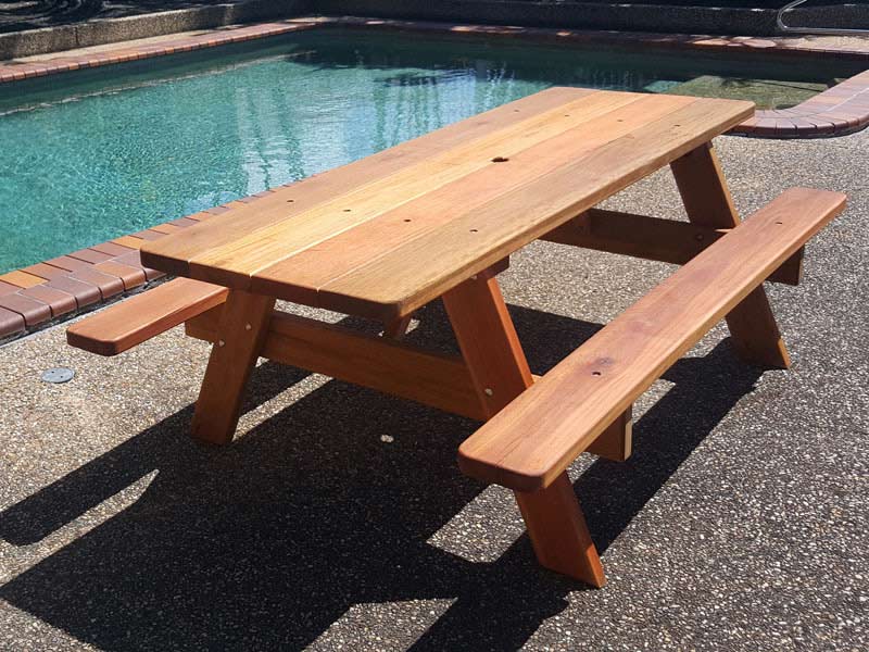 Wooden picnic table infront of an inground pool