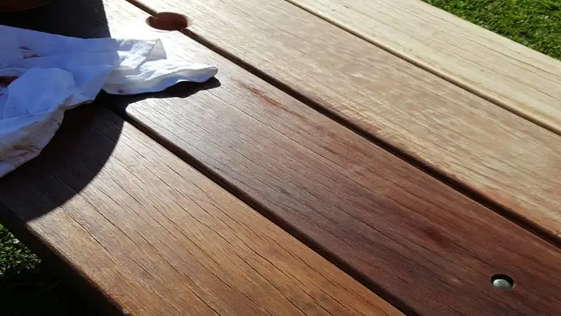 Penetrating timber oil being worked into a weathered hardwood tabletop